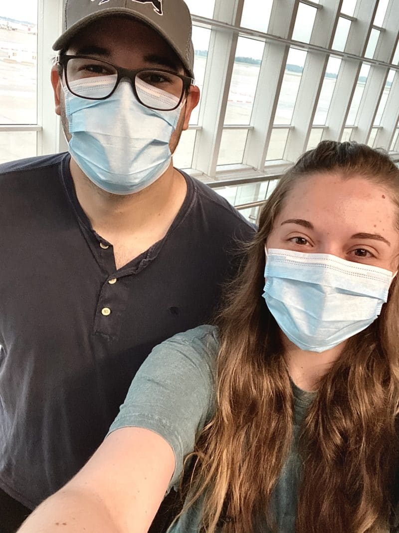 Male and female wearing masks inside of an airport, ready for holiday travel.