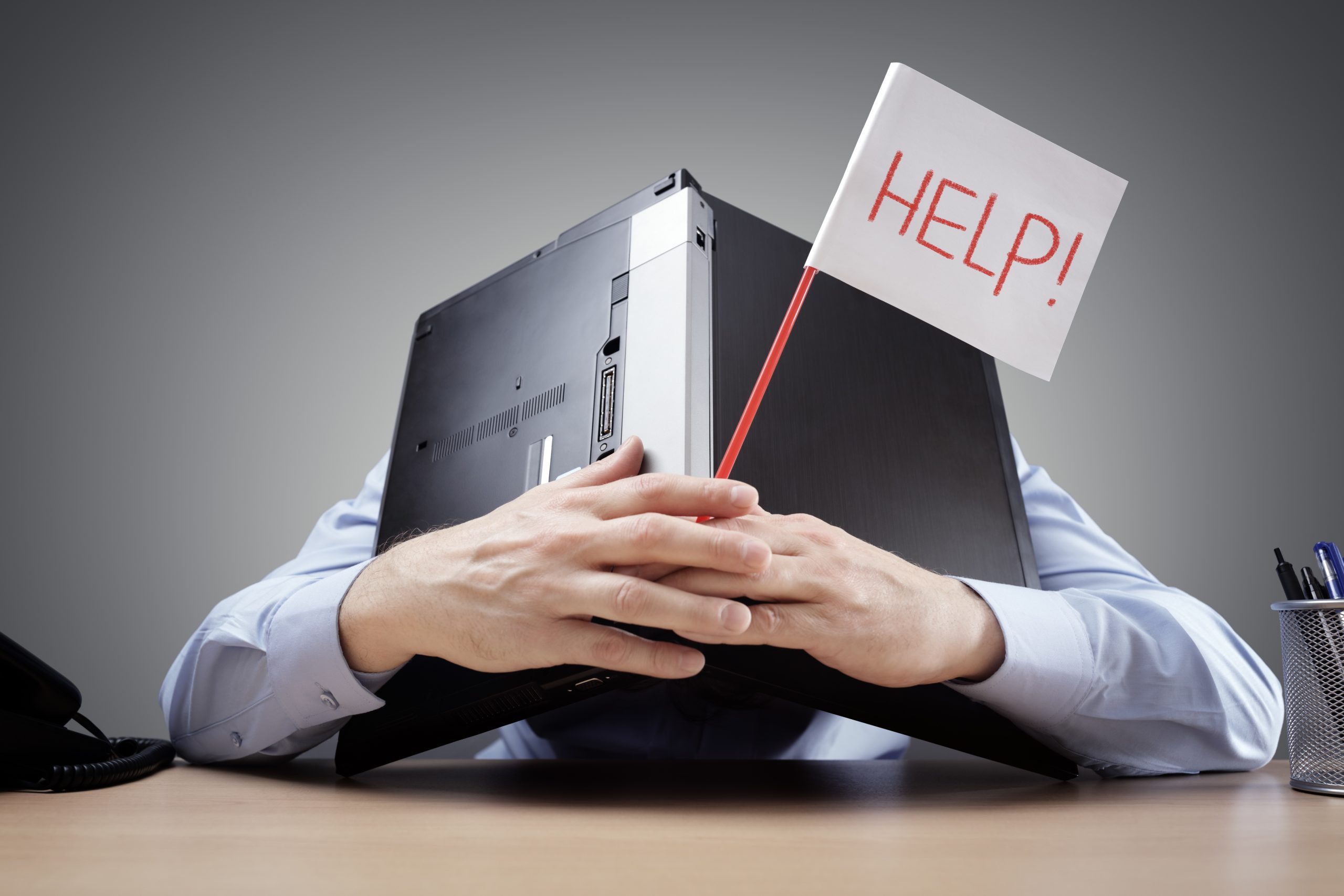 Businessman burying his head under a laptop asking for help