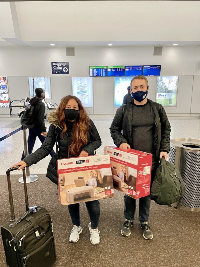 Man and woman at airport holding printers