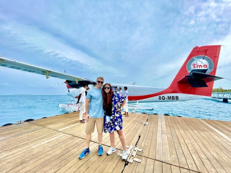 Couple standing in front of Seaplane in Maldives