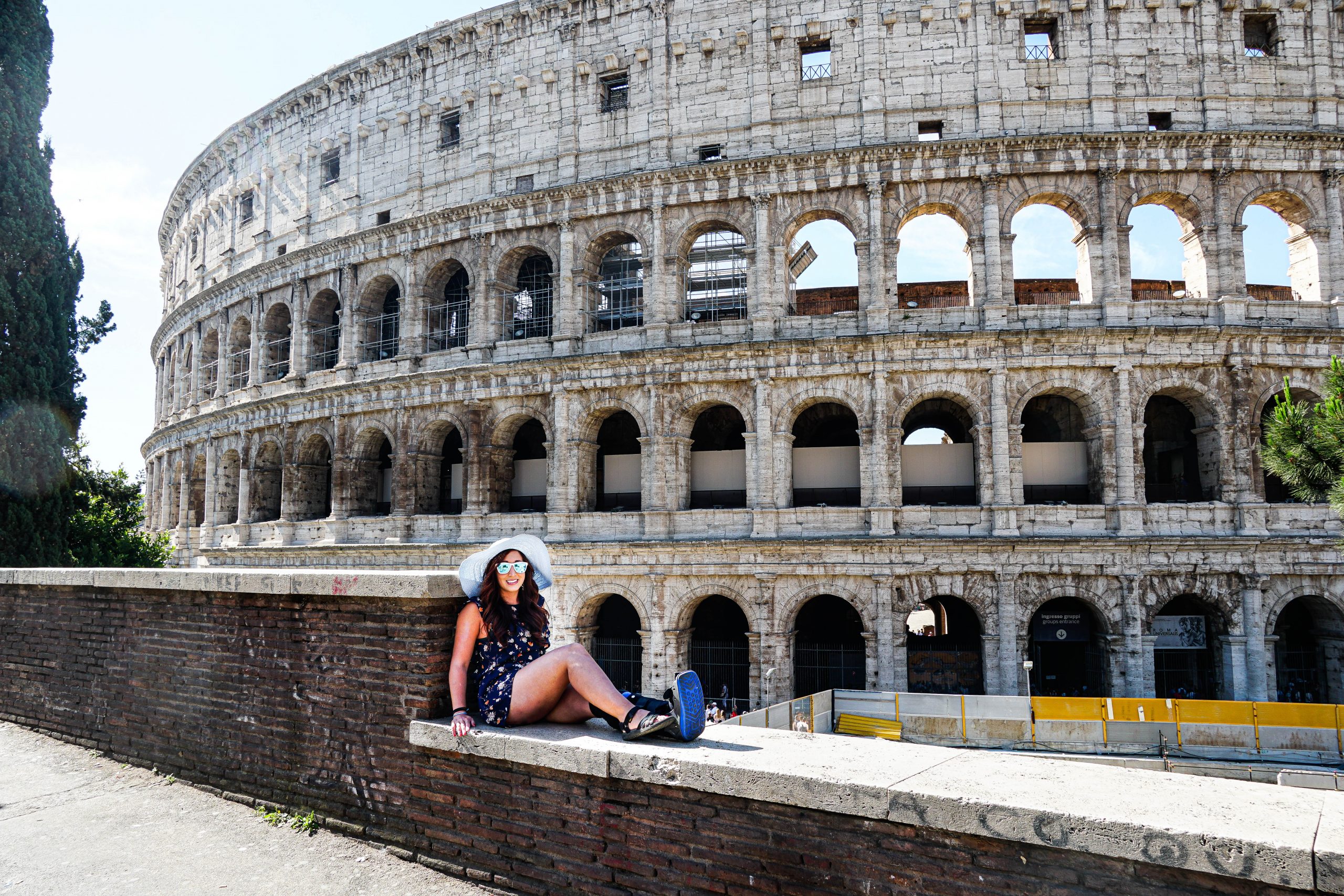 Girl in blue hat sitting in front of Roman Colosseum