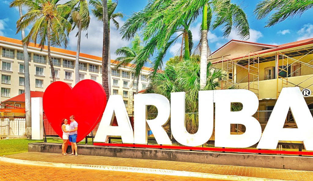 Couple posing in front of I Love Aruba Sign