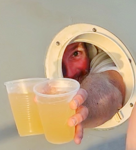 Man handing two Aruba Ariba Drinks out a boat window