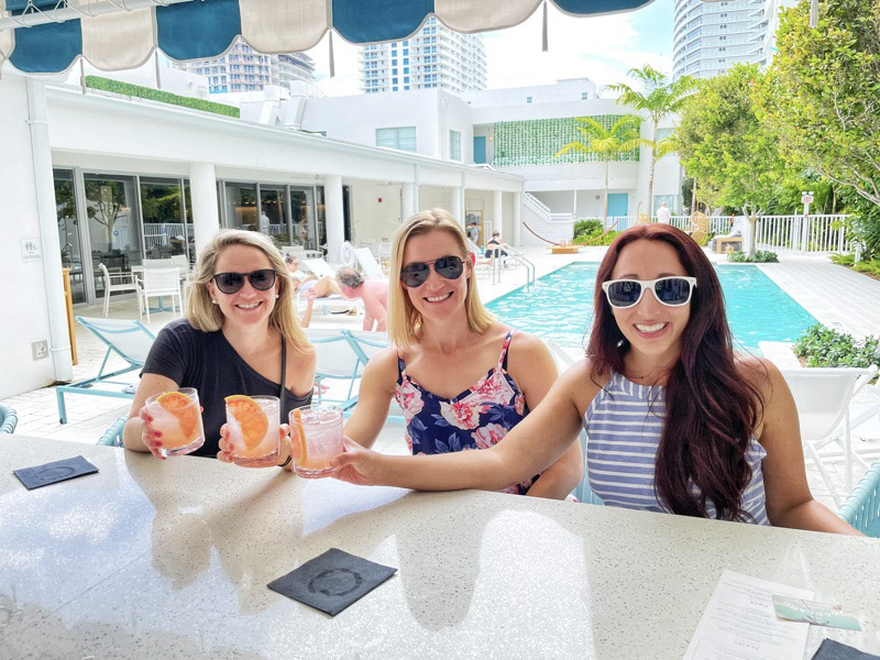3 women enjoying a drink outside at a pool bar at Kimpton Goodland Fort Lauderdale